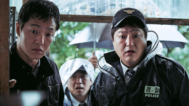 Kwak Do-won as Jong-goo, looking through a doorway with two other men in The Wailing