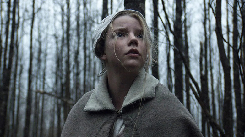 Anya Taylor-Joy as Thomasin, standing scared in the forest in The Witch