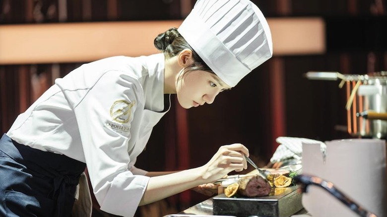 Yeon Ji-yeong (Im Yoon-ah) carefully adjusts a gourmet dish in Bon Appétit, Your Majesty