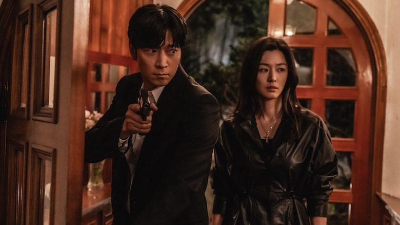Paik San-ho (Gang Dong-won) holds a pistol as he enters a room with Seo Mun-ju (Jun Ji-hyun) in Tempest