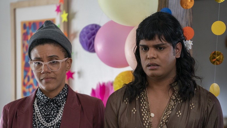 Amanda Cordner as 7ven and Bilal Baig as Sabi Mehboob standing in front of balloons and party decorations in Sort Of