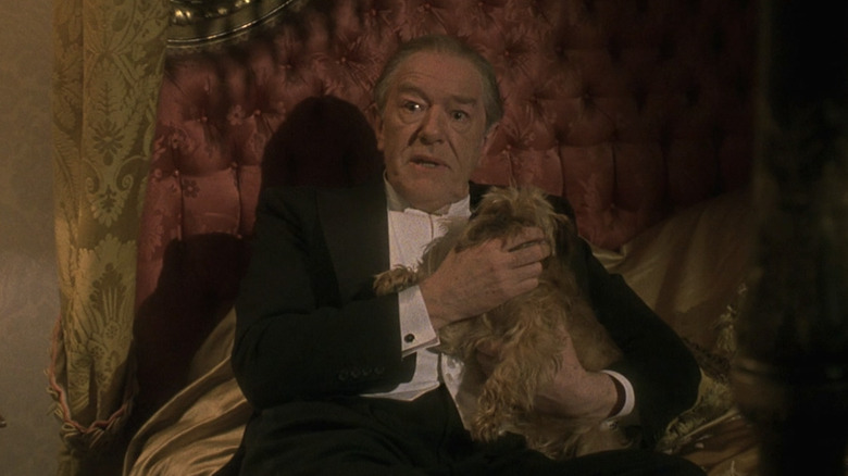 Michael Gambon as Sir William McCordle holding a dog in Godford Park