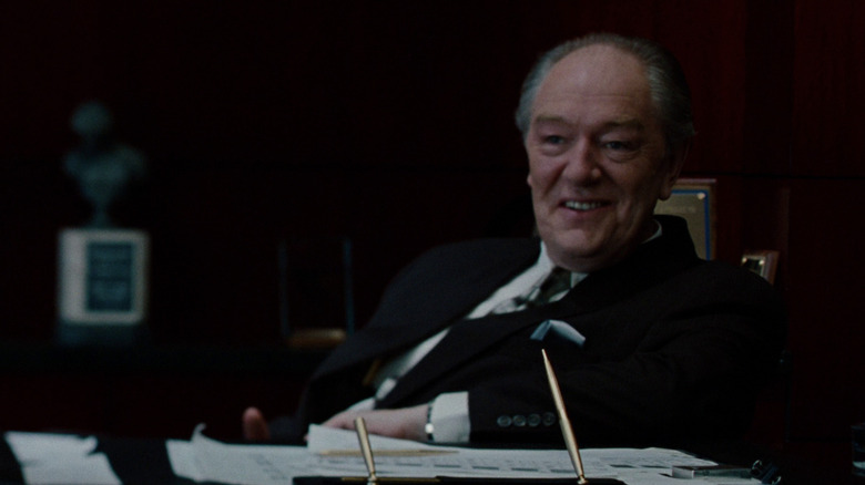 Michael Gambon as Thomas Sandefur sitting at a desk in The Insider