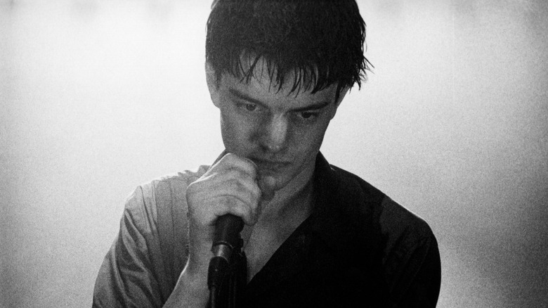 Sam Reilly as Ian Curtis holding a mic on stage in Control