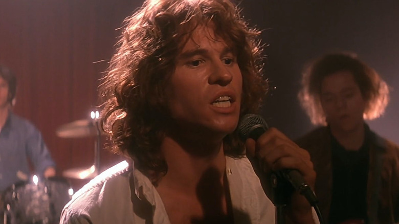 Val Kilmer as Jim Morrison on stage singing into a mic in the movie The Doors