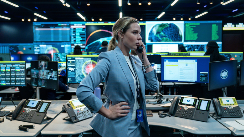 Rebecca Ferguson as Captain Olivia Walker on the phone standing in front of a desk full of computer screens in A House of Dynamite