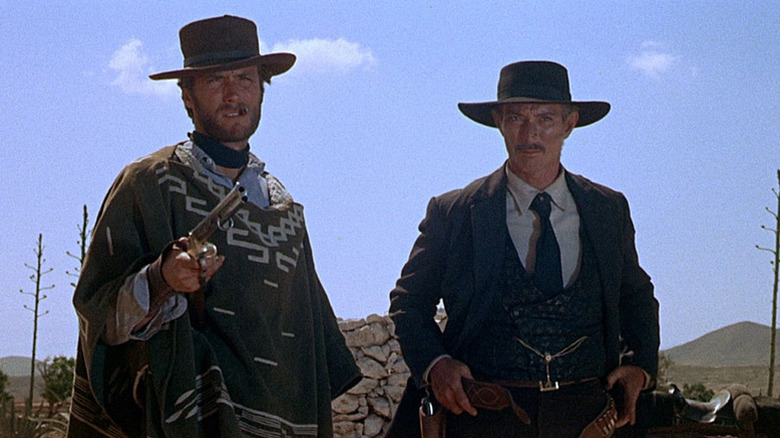 Manco (Clint Eastwood) points a rifle as Mortimer (Lee Van Cleef) watches in For a Few Dollars More
