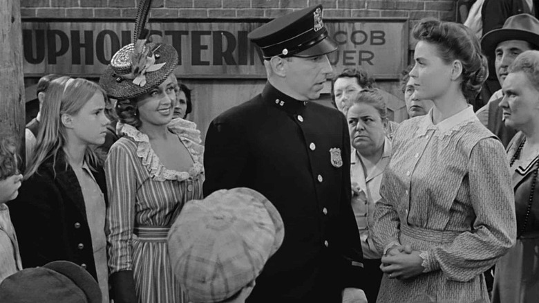 Officer McShane (Lloyd Nolan) speaks with Katie Nolan (Dorothy McGuire) surrounded by onlookers in A Tree Grows in Brooklyn