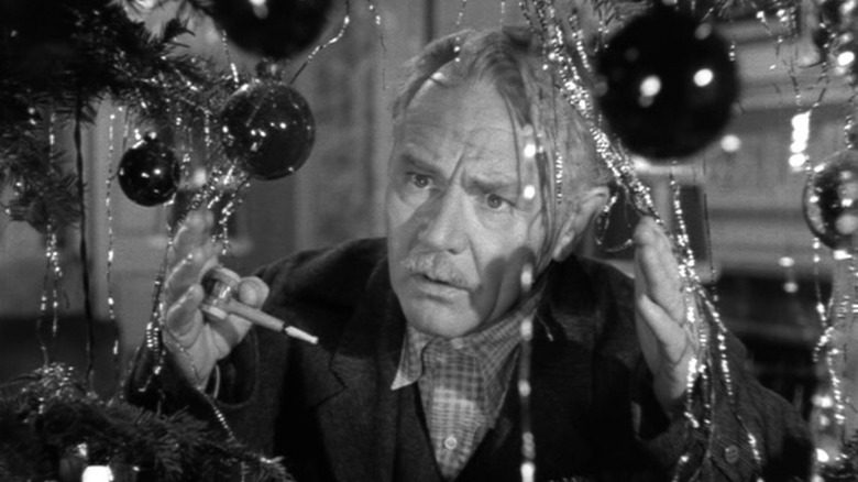A bewildered Mike O'Connor (Charlie Ruggles) peers through a Christmas tree in It Happened on 5th Avenue