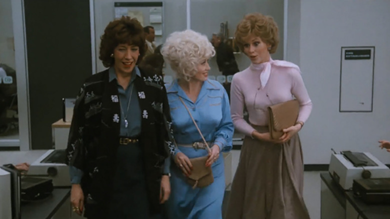 Lily Tomlin, Dolly Parton, and Jane Fonda as Violet, Doralee, and Judy linking arms in 9 to 5