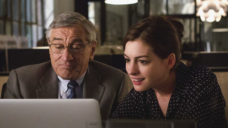Robert De Niro and Anne Hathaway as Ben and Jules looking at a computer in The Intern