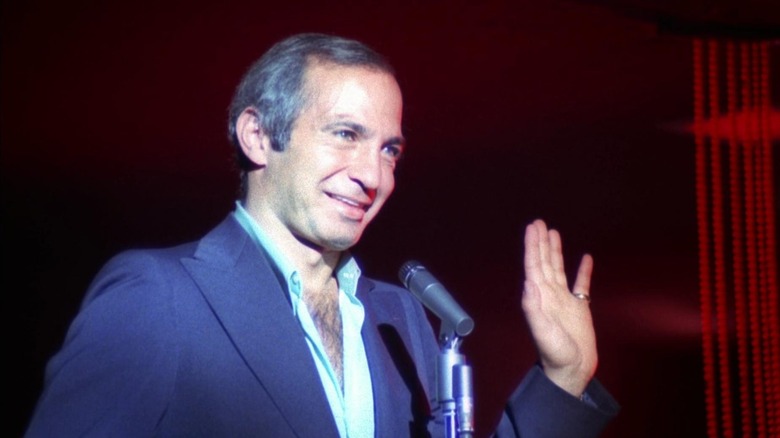 Cosmo Vittelli (Ben Gazzara) waving and talking into a microphone in The Killing of a Chinese Bookie