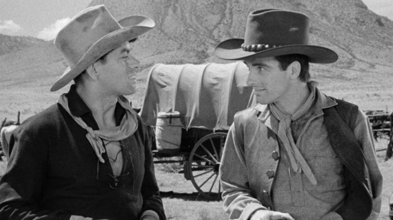John Ireland as Cherry Valance and Montgomery Clift as Matt Garth talking to each other and smiling in Red River