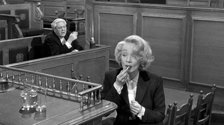 Charles Laughton as Sir Wilfrid Robarts watching while Marlene Dietrich as Christine Vole applies makeup in the courtroom in Witness for the Prosecution