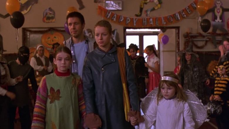 Sarah Bolger as Christy, Paddy Considine as Johnny, Samantha Morton as Sarah, and Emma Bolger as Ariel walking through a school gymnasium with Halloween decorations in In America