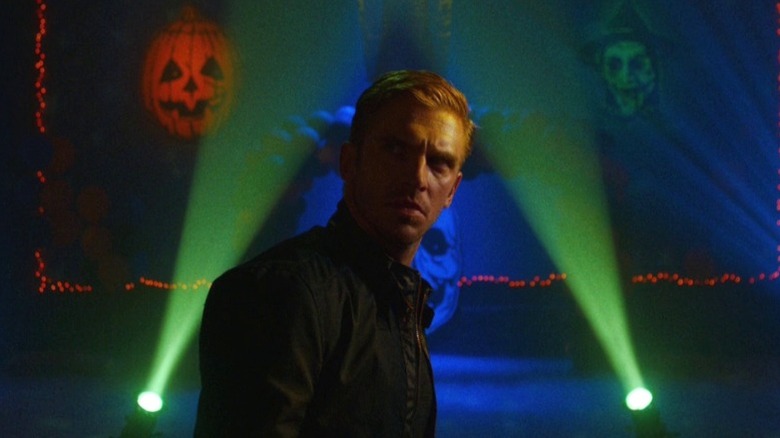Dan Stevens as David Collins surrounded by Halloween decoration and lights in The Guest