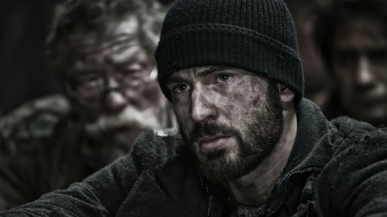 A dirtied Curtis Everett (Chris Evans) sits solemnly in Snowpiercer