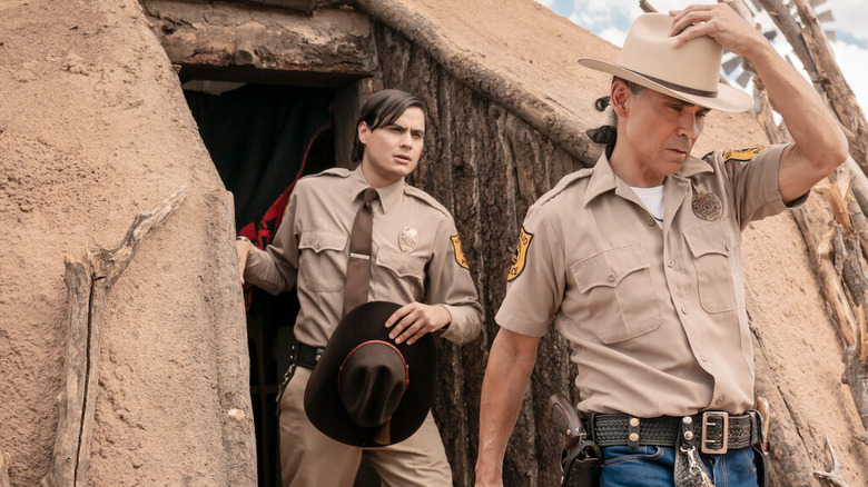 Joe Leaphorn (Zahn McClarnon) and Jim Chee (Kiowa Gordon) walk outside of a dirt building in Dark Winds
