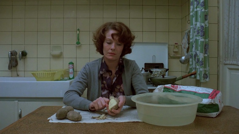 Delphine Seyrig as Jeanne Dielman in Jeanne Dielman, 23 quai du Commerce, 1080 Bruxelles, sitting at the kitchen table and peeling a potato.
