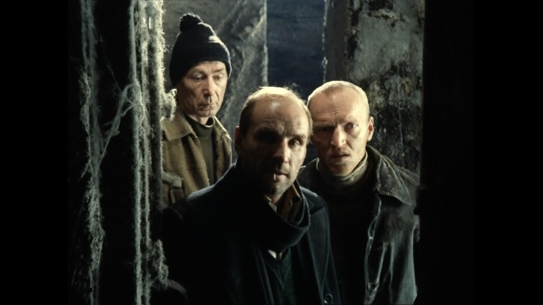 Nikolay Grinko as the Professor, Aleksandr Kaydanovskiy as the Stalker, and Anatoliy Solonitsyn as the Writer in Stalker, standing together looking into a doorway.
