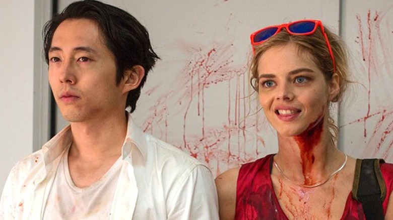 Derek (Steven Yeun) and Melanie (Samara Weaving) stand blood-splattered in Mayhem.