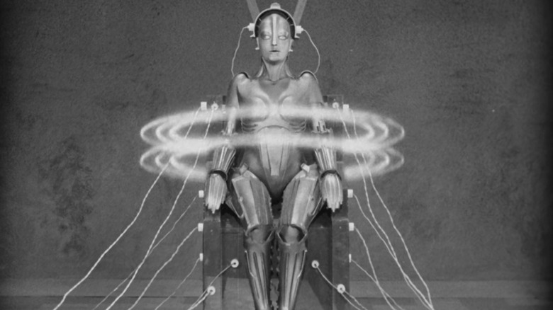 Brigette Helm as the Machine Human in Metropolis, hooked up to a futuristic char and surrounded by halos of light.