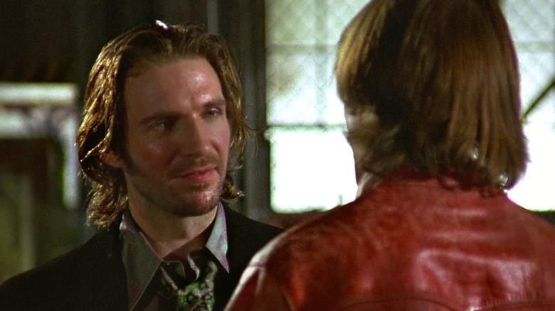 Ralph Fiennes as Lenny Nero, having a conversation with someone in an over-the-shoulder shot behind another character.