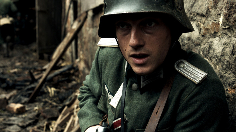 Friedhelm Winter (Tom Schilling) huddles by a stone wall in Generation War