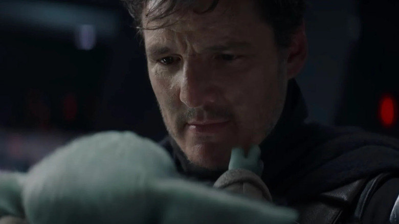 Pedro Pascal as Din Djarin looking at Grogu in The Mandalorian