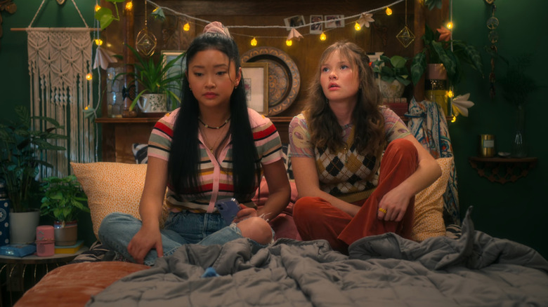 Erika (Lana Condor) and Gia (Zoe Colletti) sitting on bed in Boo B****