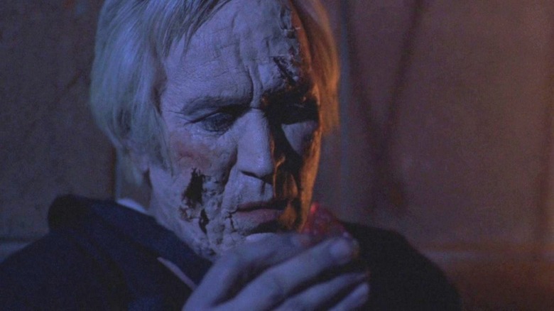 Jesus Gris (Federico Luppi) peels dead skin off of his face in Cronos (1993).