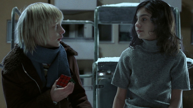 Oskar (Kåre Hedebrant), holding a rubix cube, and Eli (Lina Leandersson) share a moment together outside in Let The Right One In (2008).