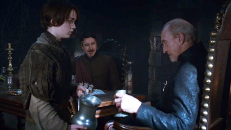 Aidan Gillen as Littlefinger watching Maisie Williams as Arya pouring a drink for Charles Dance as Tywin in Game of Thrones