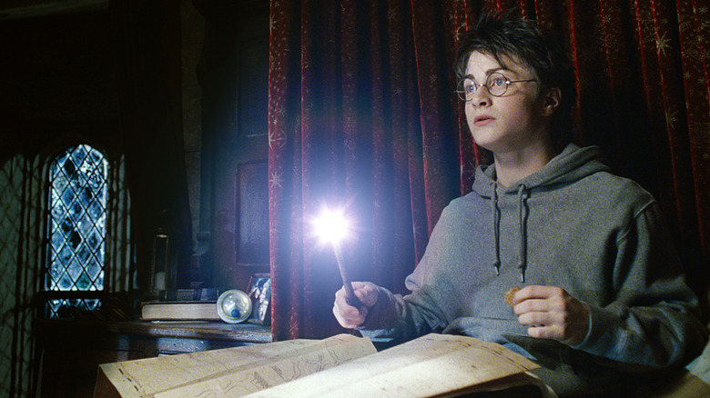 Danielle Radcliffe as Harry Potter holds a wand over the Marauder's Map
