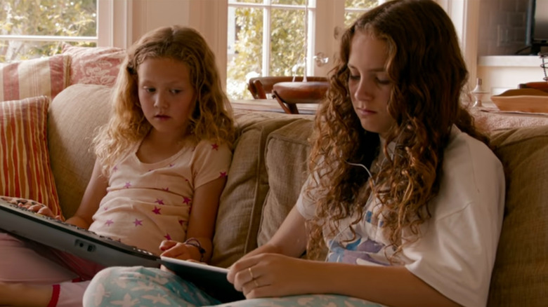 Sadie (Maude Apatow) and Charlotte (Iris Apatow) looking at tablets in This Is 40