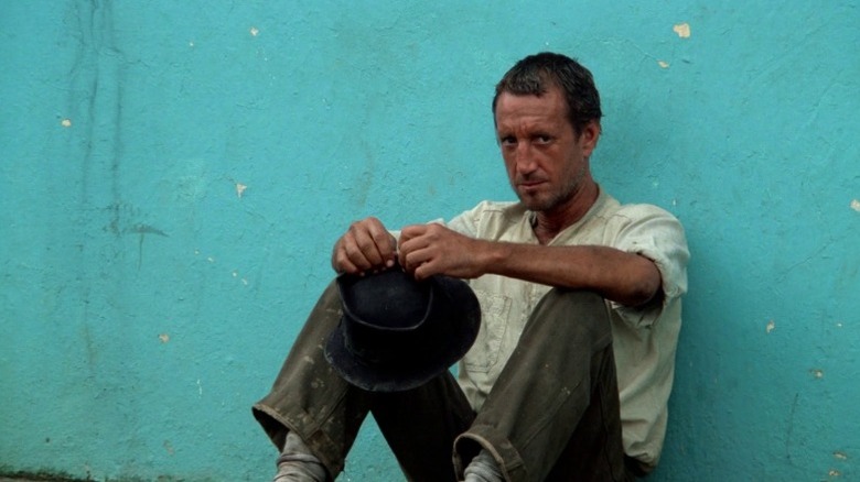 Roy Scheider as Scanlon sitting on the ground and leaning his back against a blue wall in Sorcerer