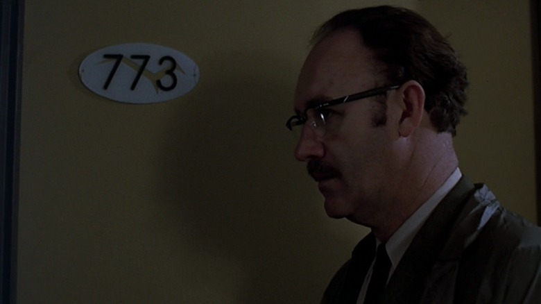 Gene Hackman as Harry Caul standing next to a door with the number 773 in The Conversation