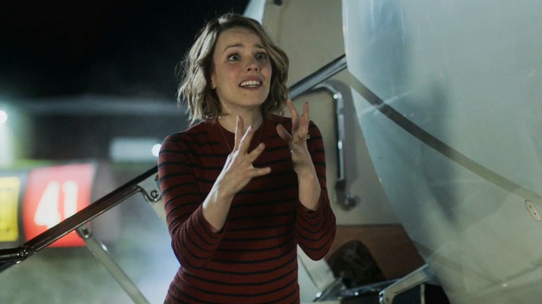 Annie Davis looks shocked standing next to an airplane in Game Night (2018).