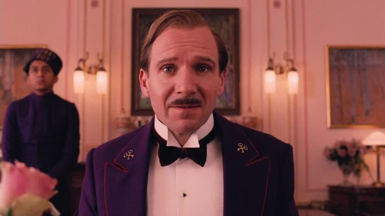 Monsieur Gustave H. (Ralph Fiennes) sits in front of lobby boy Zero (Tony Revolori) in The Grand Budapest Hotel (2014).