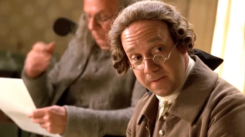 John Adams (Paul Giamatti) looking over tiny glasses in John Adams