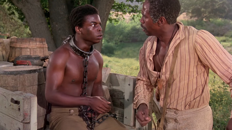 Kunta Kinte (LeVar Burton) sitting in cart in chains with Fiddler (Louis Gossett Jr) in Roots