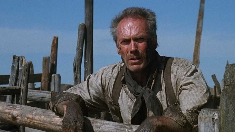 Will Munny (Clint Eastwood) leans against a wooden fence in Unforgiven