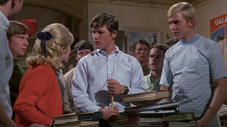 Kurt Russell as Dexter standing next to piles of books in The Computer Wore Tennis Shoes