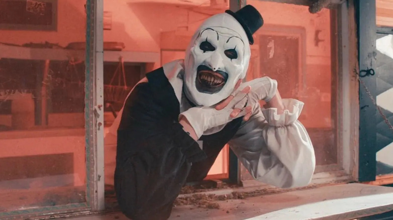 Art the Clown (David Howard Thornton) smiling out of a window in Terrifier 2