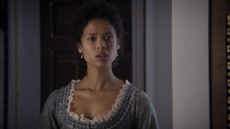 Gugu Mbatha-Raw as Dido Elizabeth Belle standing in a light blue dress with a concerned expression in Belle
