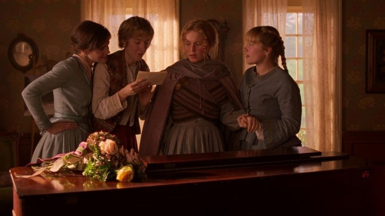 Saoirse Ronan as Jo March holding a letter as Emma Watson as Margaret March, Eliza Scanlen as Beth March, and Florence Pugh as Amy March stand around her in Little Women
