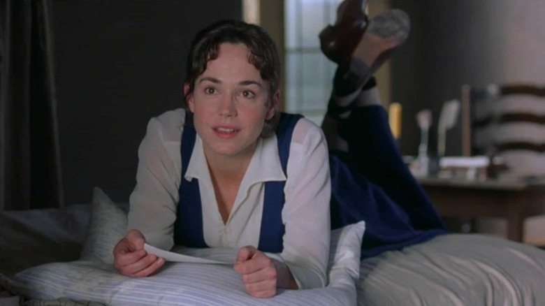 Frances O'Connor as Fanny Price lying on a bed with her feet up and looking wistfully out a window in Mansfield Park