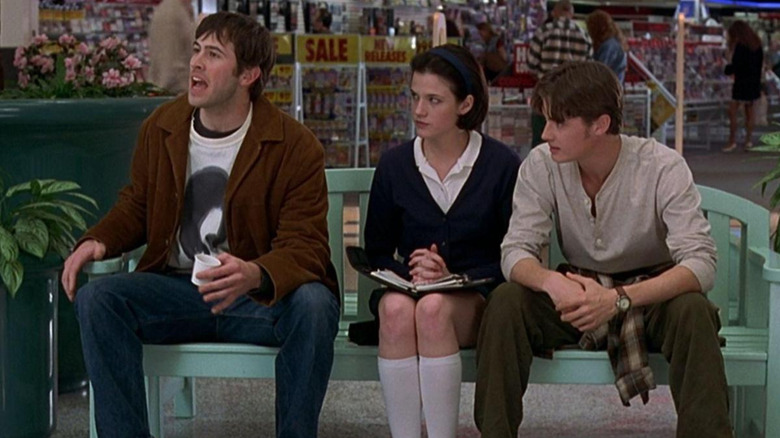 Brodie (Jason Lee) shouts at someone while sitting on a bench with Tricia (Renee Humphrey) and TS Quint (Jeremy London) in Mallrats