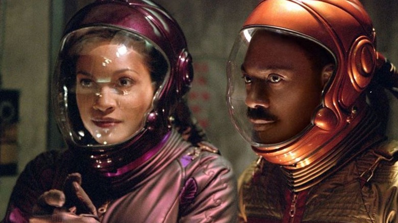 Rosario Dawson and Eddie Murphy as Dina and Pluto wearing purple and orange spacesuits respectively in The Adventures of Pluto Nash