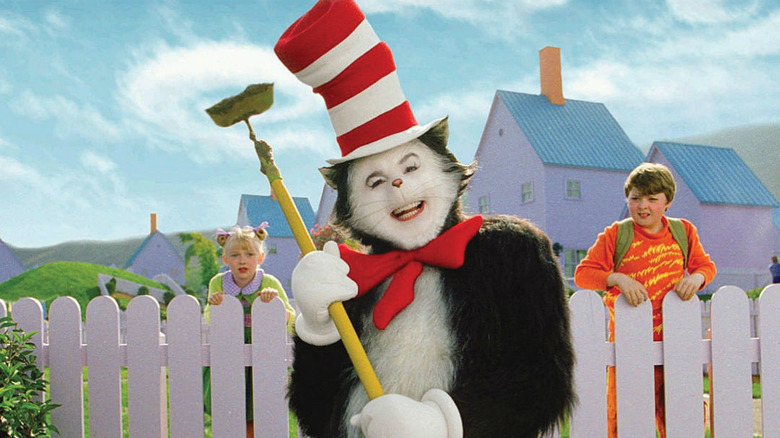 Mike Myers as the Cat holding a gardening hoe as Dakota Fanning as Sally and Spencer Breslin as Conrad watch from behind a fence in The Cat in the Hat